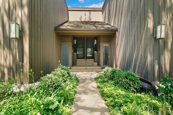 Front view of a modern house with wooden facade and entrance pathway.