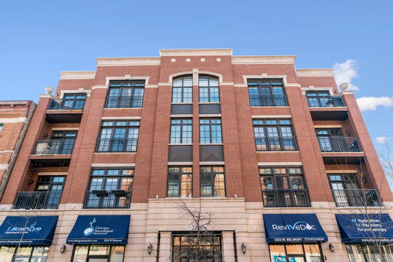 Front view of a multi-story brick building with balconies and large windows.