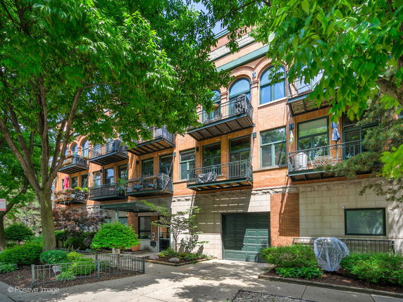 Front view of a multi-story building with balconies and a garage entrance.