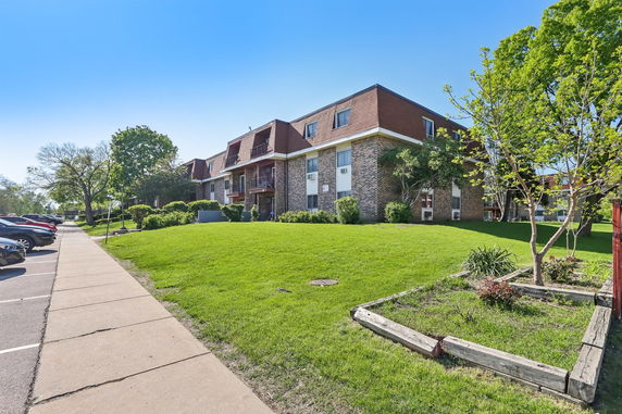 Front view of a multi-story brick apartment building with balconies.