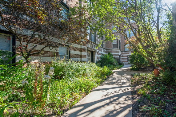 Front view of a multi-story brick building with a garden path leading to the entrance.