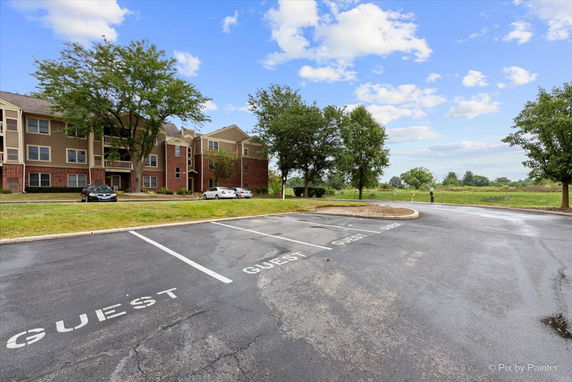 View of a parking area in front of a multi-story residential building.