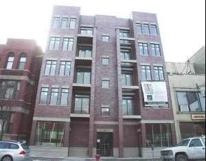 Front view of a multi-story brick building with balconies and large windows.