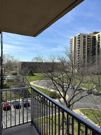 View from a balcony showing surrounding high-rise buildings and parking lot.