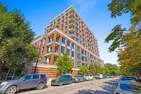 Front view of a multi-story brick apartment building with multiple balconies.