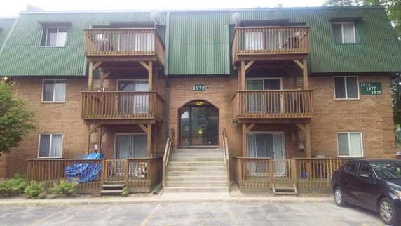 Front view of a multi-story apartment building with balconies and central entrance.