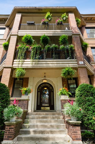 Front view of a multi-story building with balconies and decorative plants.