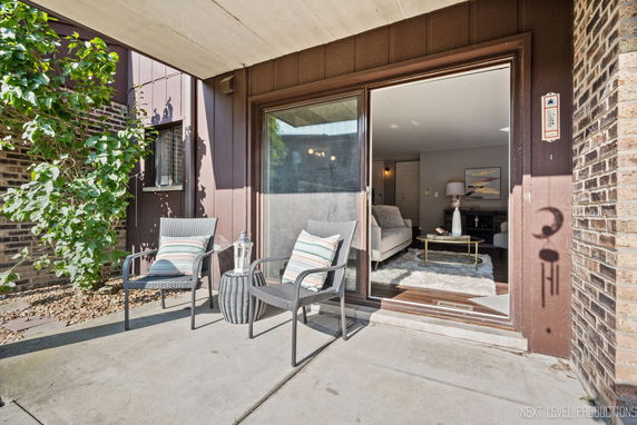 Front view of a house with a patio and sliding glass door leading to a living area.