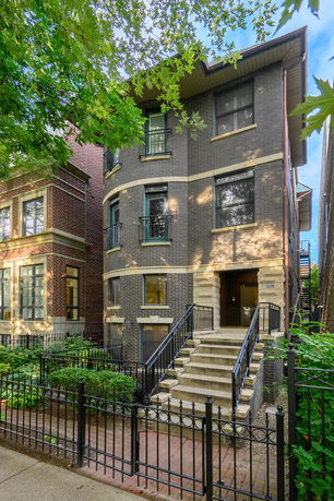 Front view of a three-story brick building with an entrance staircase and railing.