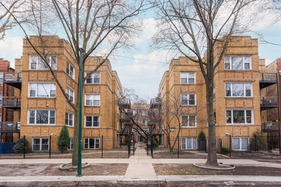 Front view of a multi-story brick apartment building with a central entrance.