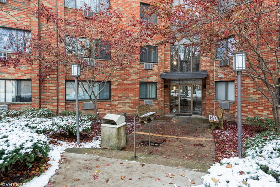 Front view of a brick apartment building with several windows and a glass entrance door.
