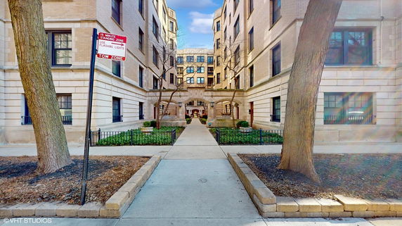 Front view of a multi-story apartment building with an archway entrance.