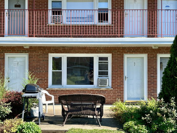 Front view of a two-story brick building with outdoor seating and a grill.