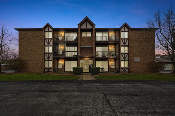 Front view of a multi-story residential building with brick facade and balconies.