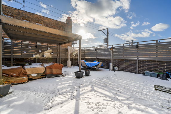 Snow-covered rooftop patio with a pergola and outdoor seating area.