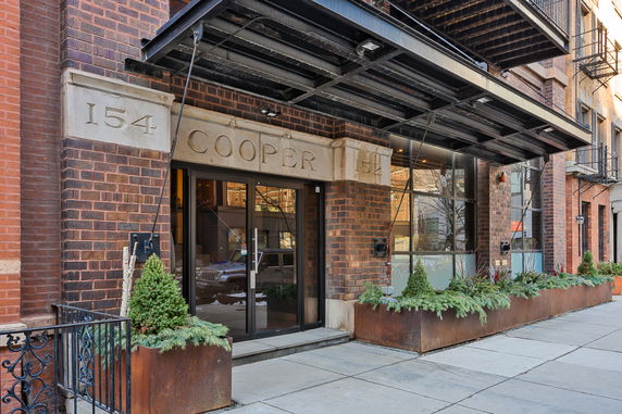 Front view of a building entrance with a large awning and planters.
