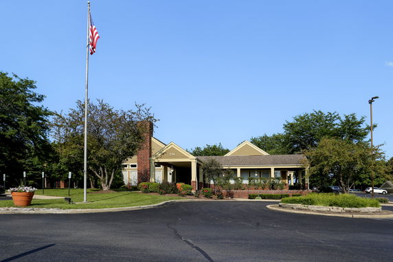 Front view of a single-story building with a chimney and surrounding trees.