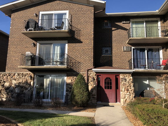 Front view of a multi-story brick apartment building with balconies.