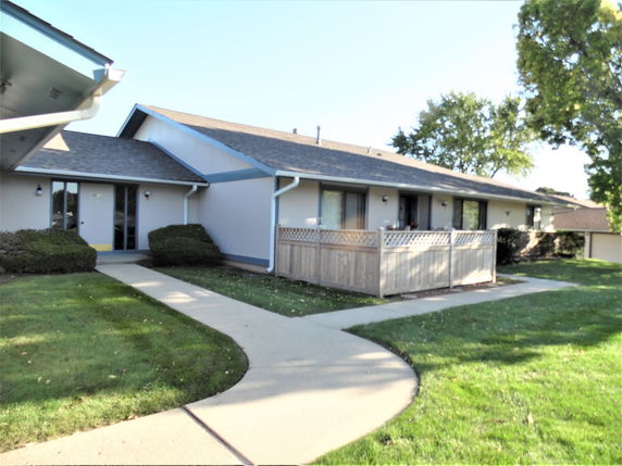 Front view of a single-story building with a sloped roof and a wooden fence.