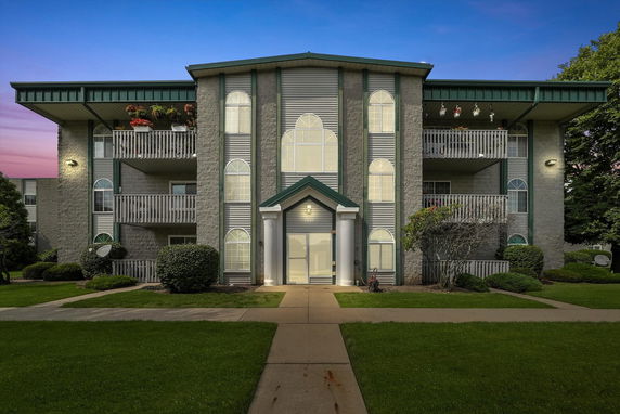 Front view of a multi-story apartment building with balconies and arched windows.