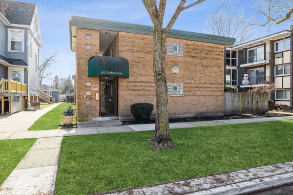 Front view of a brick condominium building with a green awning over the entrance.