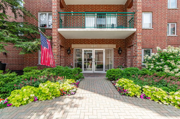 Front view of a brick apartment building with balconies and main entrance.
