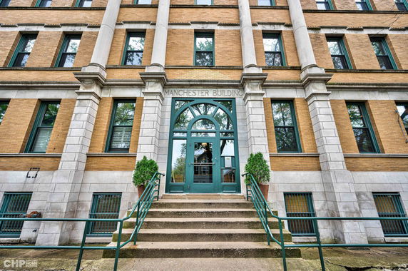 Front view of a multi-story building with stone facade and arched entrance.