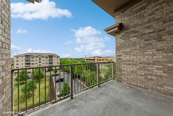 Balcony view showing nearby buildings and greenery.