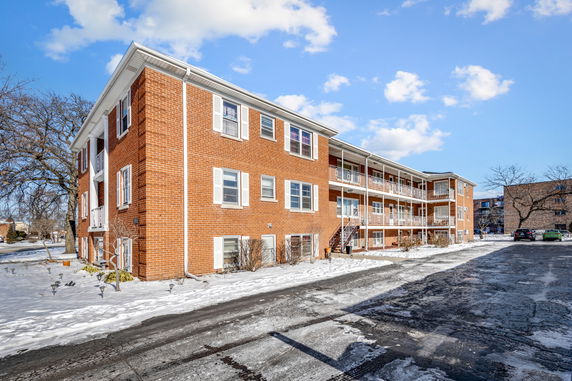 Front view of a multi-story brick apartment building with balconies.