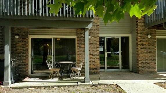 Front view of a building with a patio area and glass doors.