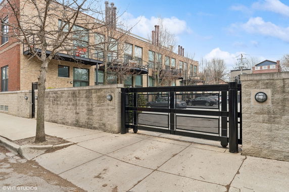 Front view of a multi-story building with large windows and a gated entry.