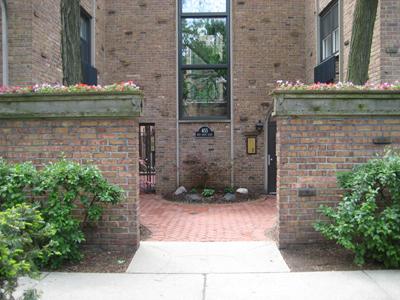 Front elevation of a brick apartment building with a garden archway entrance.