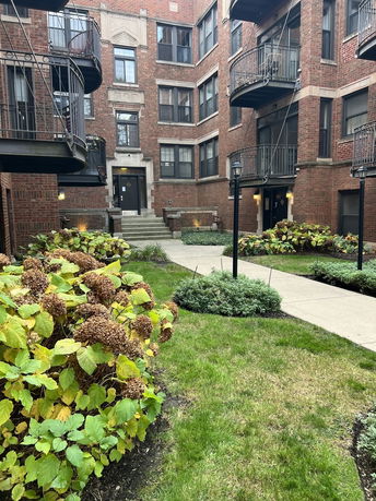 Front view of a multi-story brick apartment building with balconies.