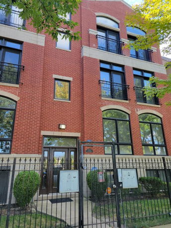 Front view of a multi-story brick building with a gated entrance.