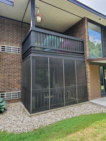 Front view of a two-story building with a screened porch and balcony.