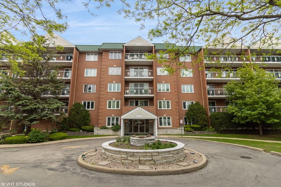 Front view of a multi-story brick apartment building with balconies.