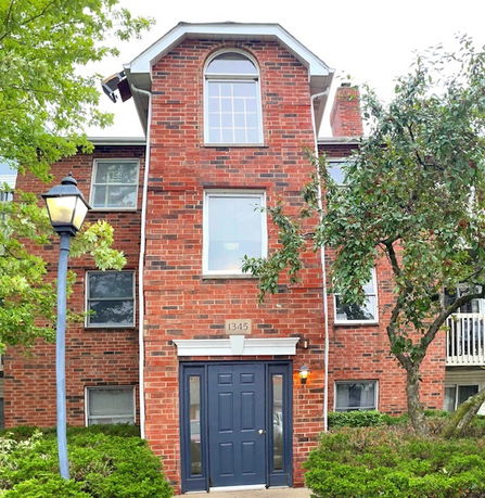 Front view of a three-story brick building with a central entrance door.
