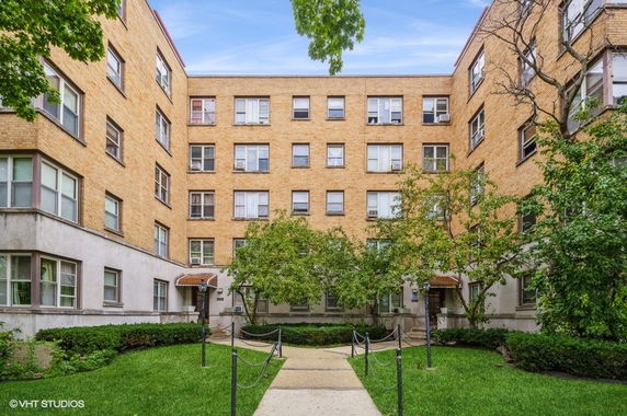 Front view of a multi-story apartment building with a courtyard.