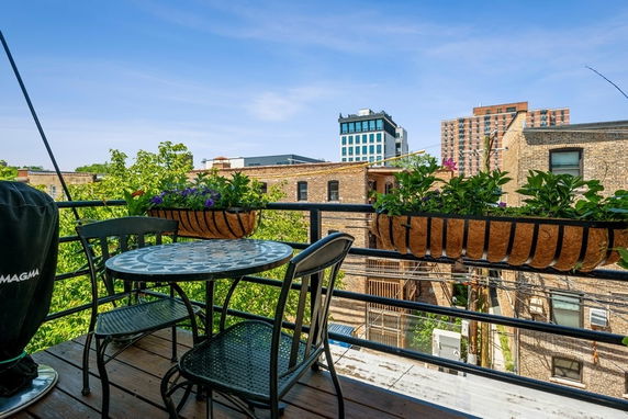 Balcony view showing surrounding buildings with patio furniture and plants.