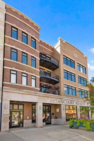 Front view of a multi-story building with brick facade and large windows.