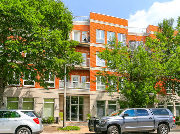 Front view of a multi-story brick apartment building with balconies.