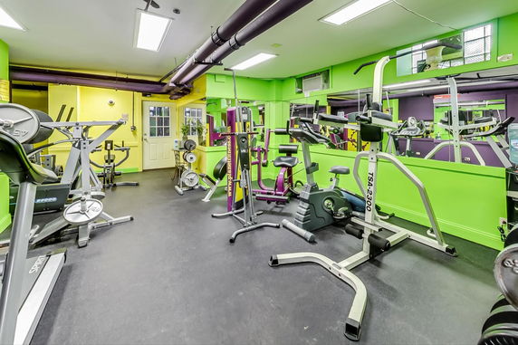 Indoor gym area with various exercise equipment and bright green walls.