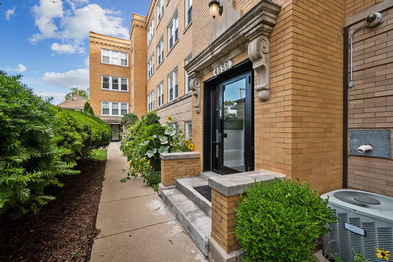 Front view of a multi-story brick apartment building with a main entrance.