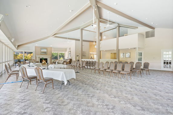 Interior of a spacious room with seating and tables set up for an event.