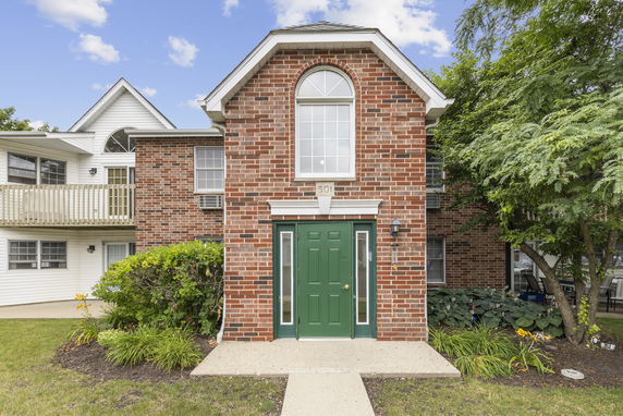 Front view of a two-story building with brick facade and green door.