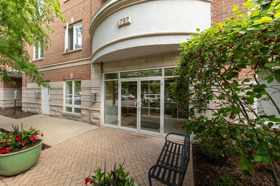 Front view of a multi-story building entrance with glass doors and brick facade.