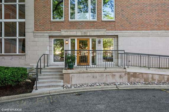 Front view of a brick building with a glass entry door and stairs leading up.