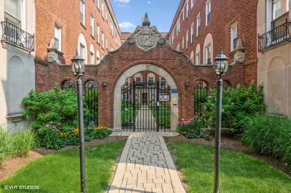 Front view of a brick building with an ornate arched entrance and gated passageway.