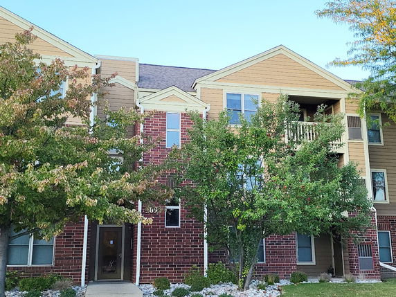 Front view of a multi-story residential building with red brick and tan siding.