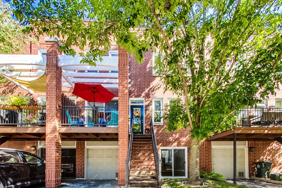 Front view of a brick multi-story house with balconies and a garage.